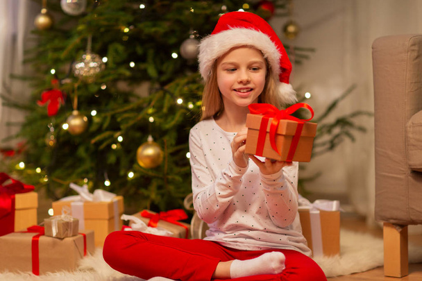 smiling girl in santa hat with christmas gift - Foto, immagini
