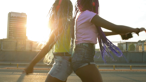 4k uhd deux sœurs noires frères et sœurs ville extérieure contre-jour en utilisant le téléphone intelligent écouter de la musique danser contre la lumière bonheur, réseau social, concept d'interaction
 - Séquence, vidéo