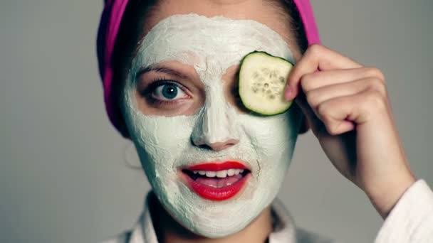 Close up of a girl with a face mask and a towel on her head that close her eyes with cucumbers. The concept of skin care. - Filmati, video