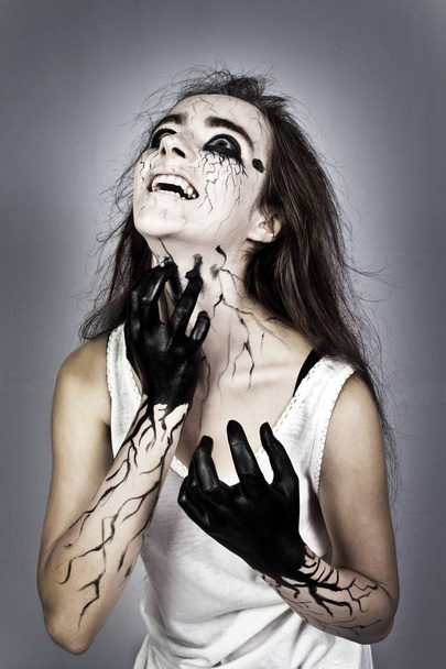 Halloween. Portret. schreeuwen in het donker, een gekke meisje met zwarte aders op haar gezicht. concept van halloween en Allerzielen. - Foto, afbeelding