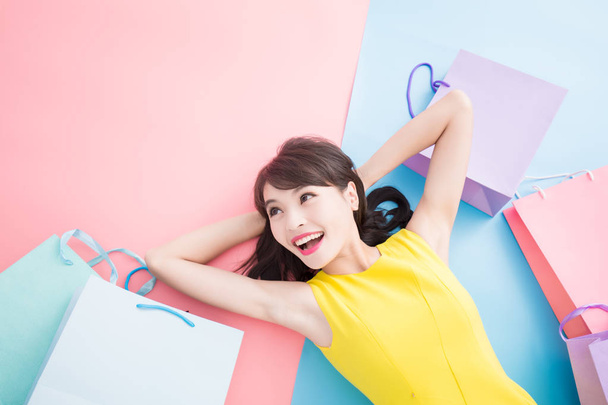mujer con bolsas de compras sonriendo felizmente sobre el fondo azul y rosa
 - Foto, imagen