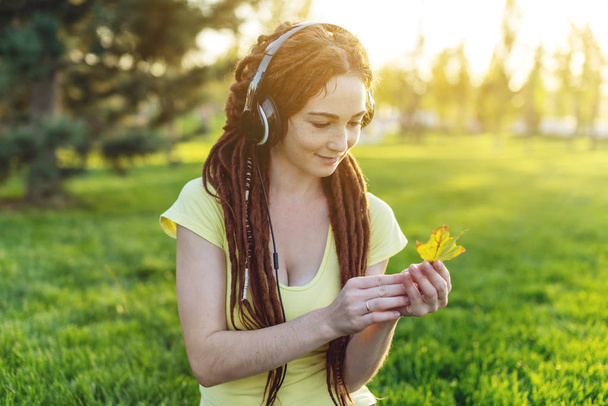 Krásná moderní žena poslechu hudby s její sluchátka na pozadí přírody na podzim Sunny Park. Pojem dobré nálady, oblíbenou hudbu, happy time. - Fotografie, Obrázek