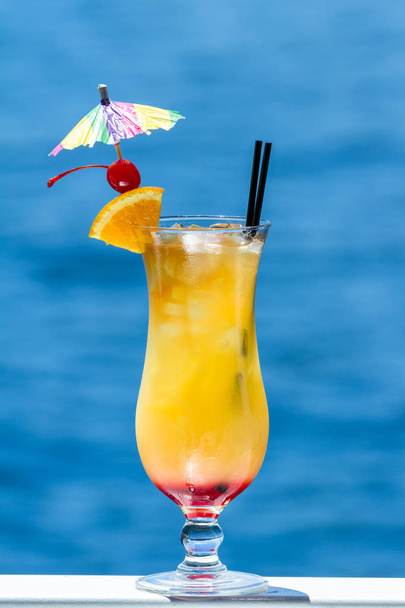 cocktail tropical servido no exterior com um fundo natural azul água como um conceito de férias de viagem
 - Foto, Imagem