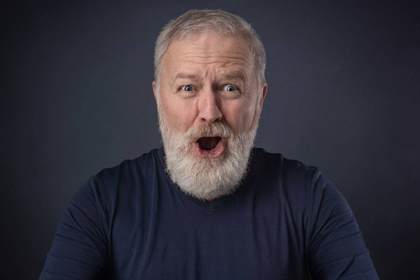 An elderly man with a gray beard with a very surprised mimic - Photo, Image