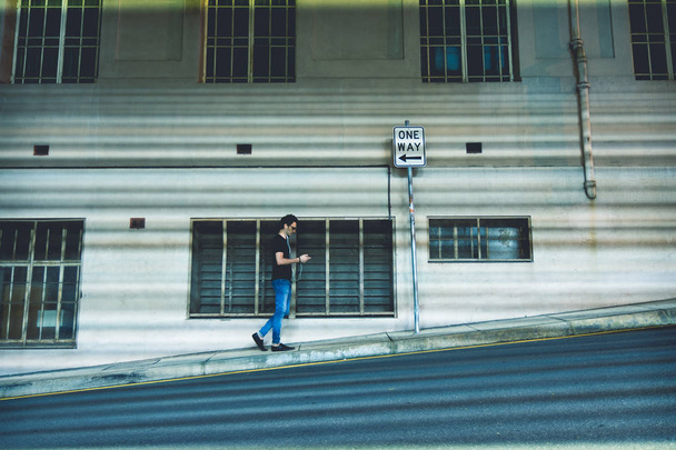 Вид збоку особи з сонцезахисні окуляри, прослуховування музики та пішохідного руху на авеню біля будівлі в Брісбен, Австралія - Фото, зображення