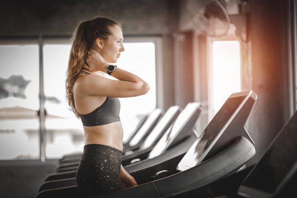 Fit young woman caucasian running on machine treadmill workout in gym. Glad smiling girl is enjoy with her training process. Concept of fitness, healthy life, Sport, Lifestyle. - Photo, Image