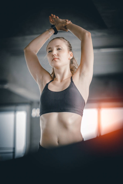Young woman attractive fitness exercise workout in gym. Woman stretching the muscles and relaxing after exercise on machine treadmill at fitness gym club. - 写真・画像