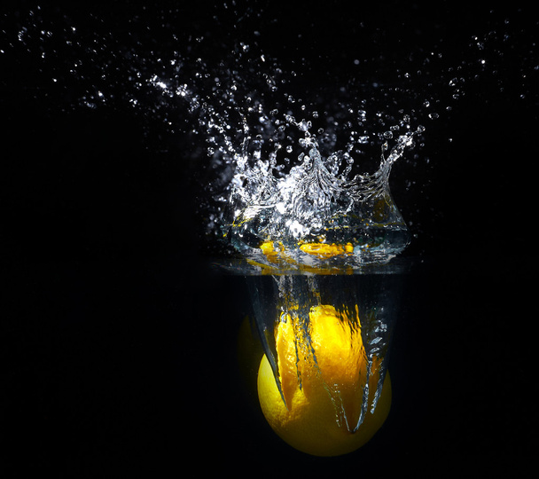 Tuore keltainen sitruuna putoaa veteen tilkka vettä
 - Valokuva, kuva