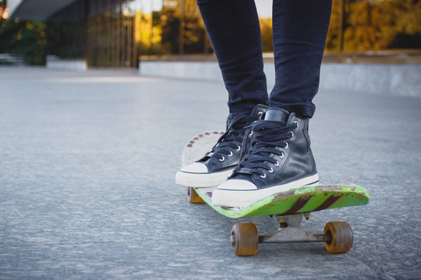 Skateboarder με ένα skateboard με το υπόβαθρο του δρόμου, μαλακή εστίαση - Φωτογραφία, εικόνα