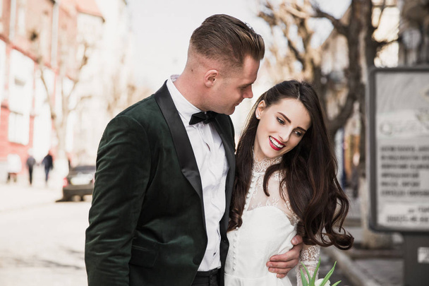 Portrait of the young happy couple who is standing in embrace outdoor in their big day - Foto, Imagem