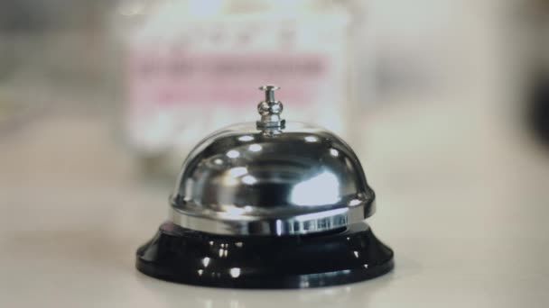 Ludzką ręką dzwonka usługi srebrny dzwon na recepcji hotelu - Materiał filmowy, wideo