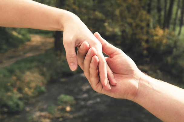 Mans dłoń delikatnie trzymając kobieta na tle strumień wiosna, pojęcie miłości i Walentynki - Zdjęcie, obraz