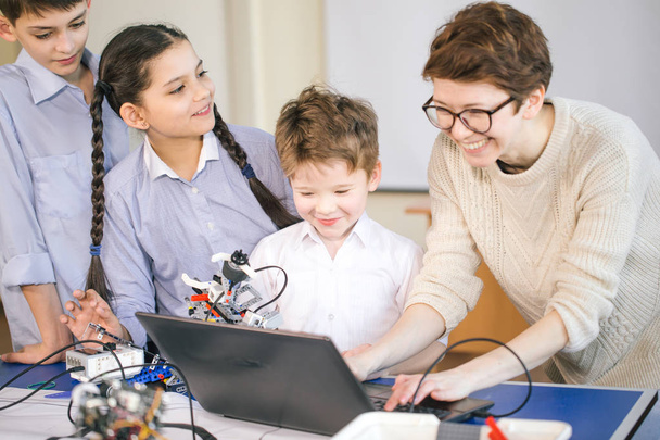 groupe d'enfants heureux avec leur femme adulte science prof avec tablette PC programmation de jouets électriques et robots à la robotique club de passe-temps - Photo, image