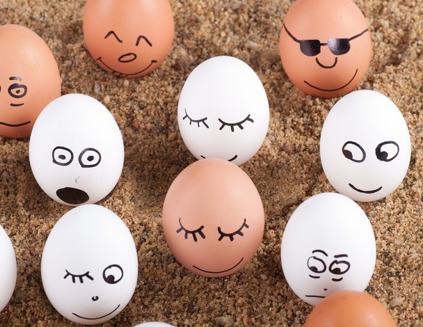 group of Funny crazy smiling eggs on a sand - Foto, Imagen