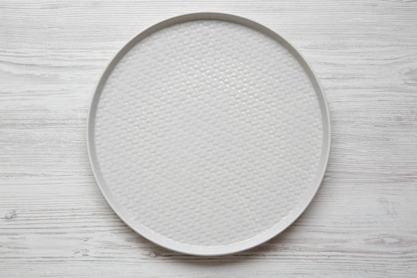 Grey round plate on white wooden background, top view. Flat lay, overhead, from above. - Photo, Image