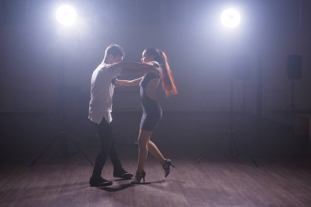Giovane coppia che balla social danse kizomba o bachata o semba o taraxia in fondo alla classe di danza
. - Foto, immagini