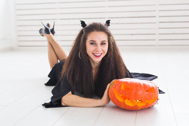 Nadšený šťastná mladá žena v halloween kostýmu pózuje s vyřezávanou dýni v lightroom - Fotografie, Obrázek