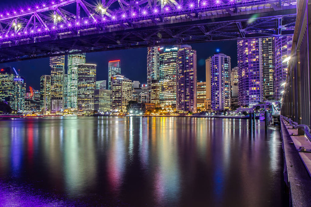 Felle gloeiende lichten van moderne stad wolkenkrabbers weerspiegelen in golfde water van de rivier, Brisbane - Foto, afbeelding