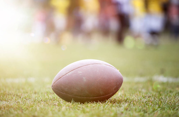Close up of an american football on the field, players in the background - Valokuva, kuva