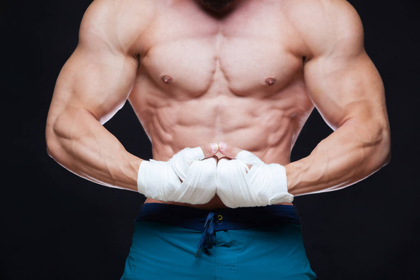 Muscular Fighter kickbox With white Bandages against the black background. - Photo, Image