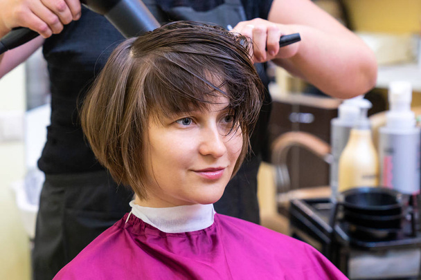 Красивая молодая женщина в парикмахерской стрижется Боб
 - Фото, изображение
