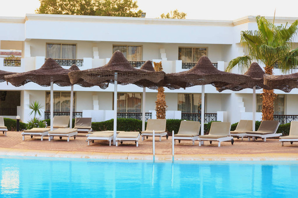 endroit pour se détendre au bord de la piscine avec chaises longues et parasols
 - Photo, image