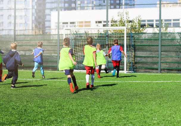 サッカー チーム - 赤、青、緑の制服の男の子グリーン フィールド上にサッカーします。ゲーム、トレーニング、アクティブなライフ スタイル、趣味、子供の概念のためのスポーツをチームします。 - 写真・画像