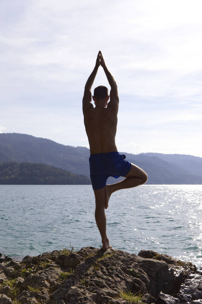Jeune homme pratique le yoga devant un lac
 - Photo, image