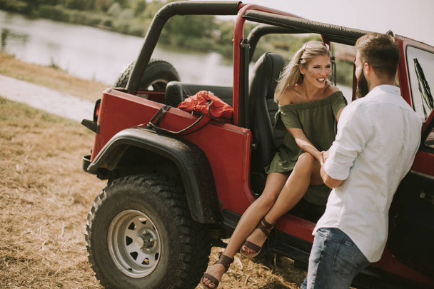 Giovane donna e uomo divertirsi all'aperto vicino auto al giorno d'estate
 - Foto, immagini