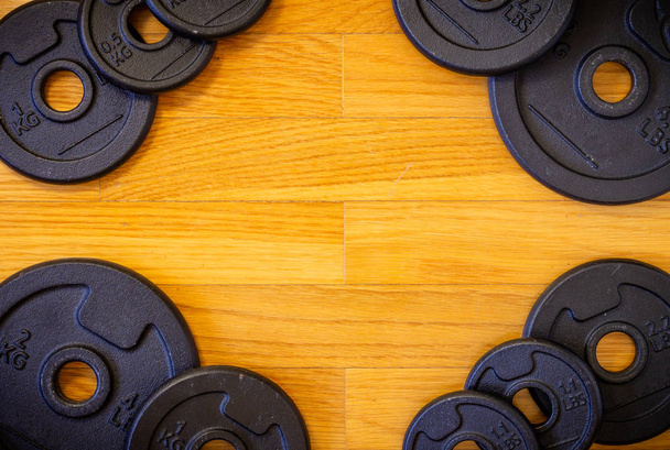 A wooden background with a set of gym equipment consisting of various dumbell weights. - Foto, Imagen