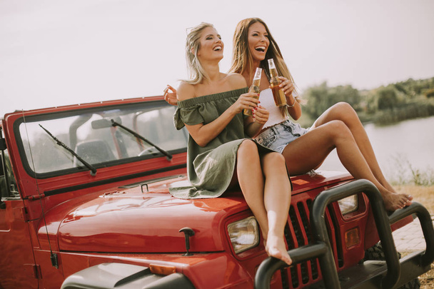 Atractivas mujeres jóvenes divirtiéndose en un coche descapotable por el río
 - Foto, Imagen