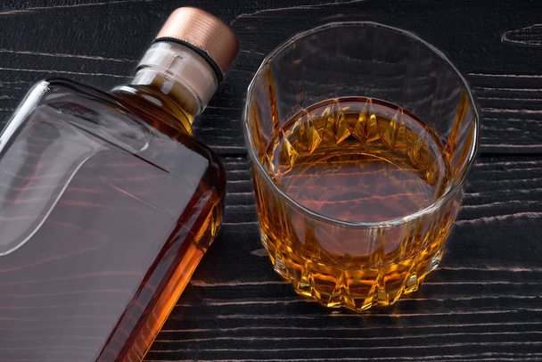 Botella llena de whisky en una mesa de madera negra.Ubicación horizontal
 - Foto, imagen