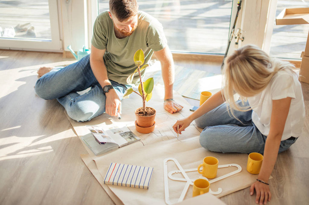 Young couple looking blueprints of they new house. Planning interior design - 写真・画像