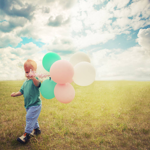Little boy playing with colorful balloons in summer meadow - Fotografie, Obrázek