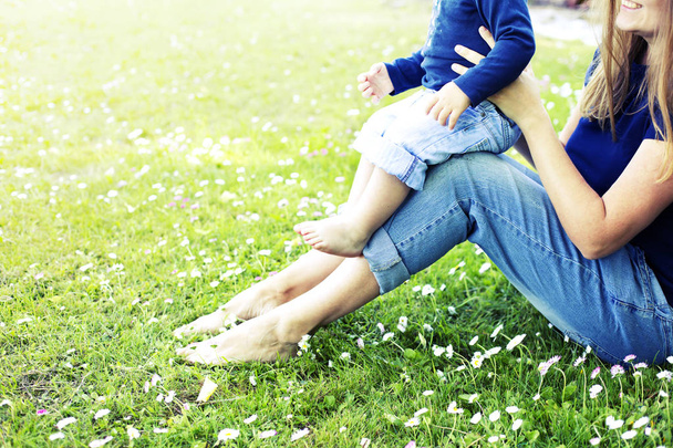 Low section of woman relaxing on green grass with baby boy - Фото, зображення