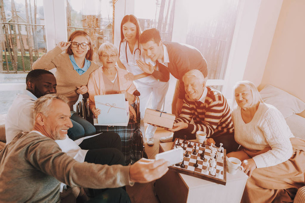 Family Selfie. Mobile Phone. Birthday Party. Celebration. Gifts. Balloons. Guests. Young and Old People. Nursing Home. Congratulate. Elderly Woman. Happy. Wheelchair. Madly Happy Retiree. Surprised. - Fotoğraf, Görsel