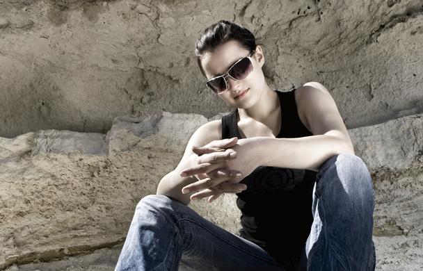 Model sitting on the rocks. Urban style - Foto, afbeelding