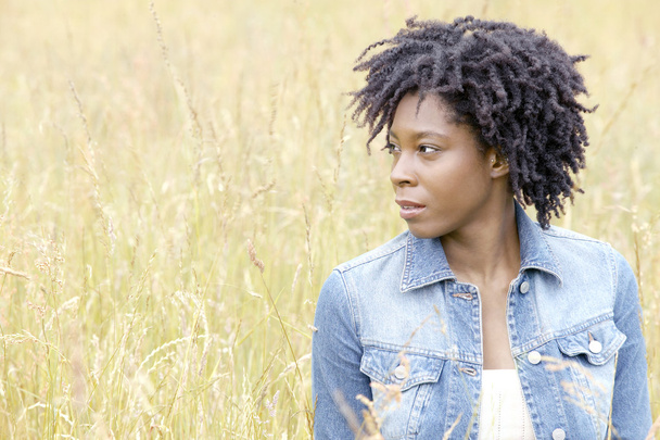 atrakcyjny czarny kobiety stojącej w polu długości trawy. - Zdjęcie, obraz