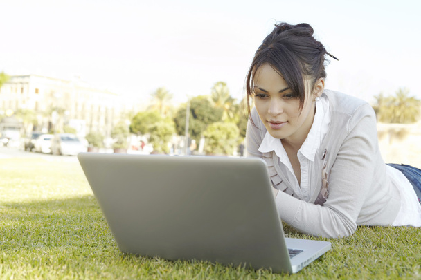 Close up de uma jovem mulher usando um laptop em um parque na cidade
. - Foto, Imagem