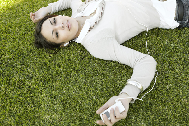 Nuori nainen makaa vihreällä ruoholla
 - Valokuva, kuva