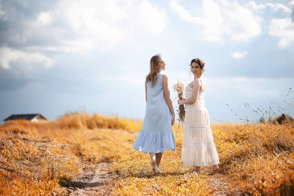 Two girls in dresses in autumn field - Fotoğraf, Görsel