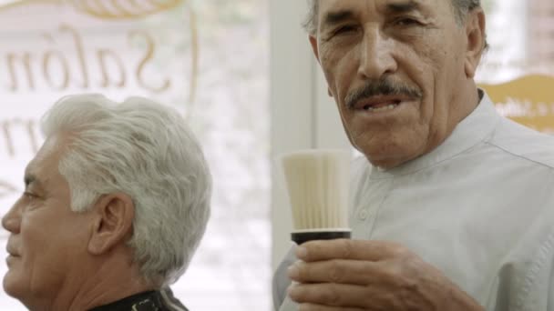 portret starszego człowieka pracy jako fryzjer w salon fryzjerski - Materiał filmowy, wideo