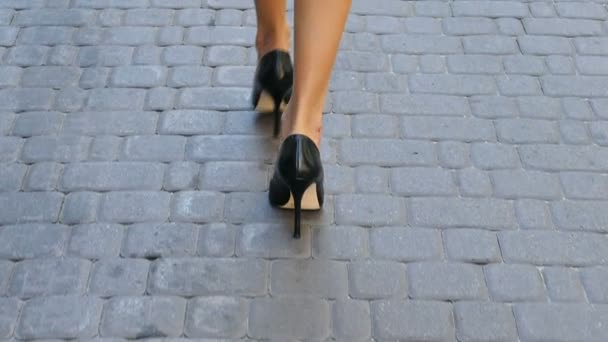 Movimento lento.. Belas pernas femininas harmoniosas de salto alto ir ao longo da rua .Visão traseira
 - Filmagem, Vídeo