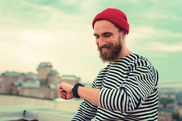 happy bearded man smiling while looking at the new watch - Zdjęcie, obraz