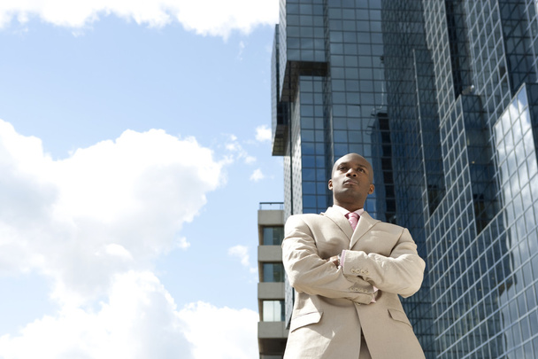 Businessman confidently standing in front of a glass office building, outdoors. - Фото, изображение