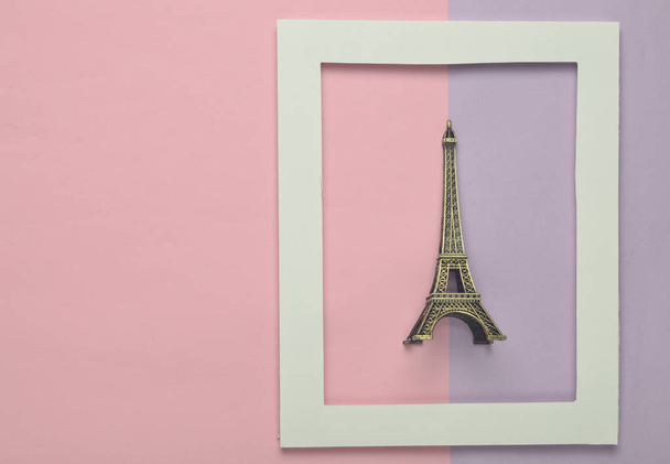 Estatuilla de recuerdo de la torre Eiffel en un marco blanco sobre un fondo pastel de colores. Tendencia minimalista. Vista superior
 - Foto, Imagen