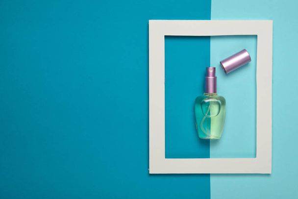 Una bottiglia di profumo in una cornice bianca su uno sfondo colorato pastello. Tendenza minimalista. Vista dall'alto
 - Foto, immagini