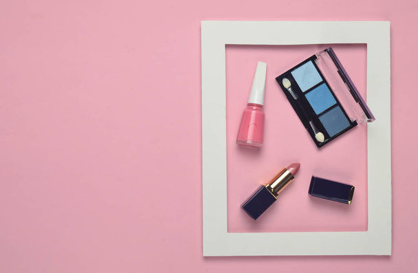 Cosmética femenina en un marco blanco sobre un fondo pastel rosa. Sombras para maquillaje, lápiz labial, esmalte de uñas. Tendencia minimalista. Vista superior. Copiar espacio
 - Foto, imagen