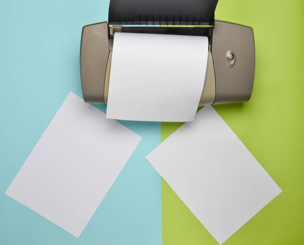 A nyomtató a színes pasztell háttér üres papír formákkal. Felülnézet, lapos laikus - Fotó, kép