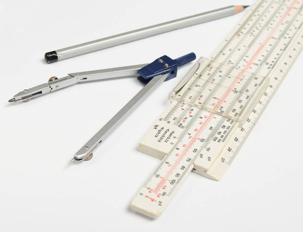 Regla logarítmica, brújulas, lápiz sobre fondo blanco. Papelería para ingenieros y estudiantes
 - Foto, Imagen